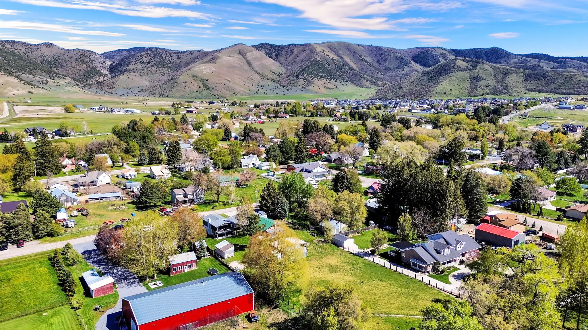 Expansive aerial perspective showcasing a residential community set against a backdrop of rolling mountains and verdant fields