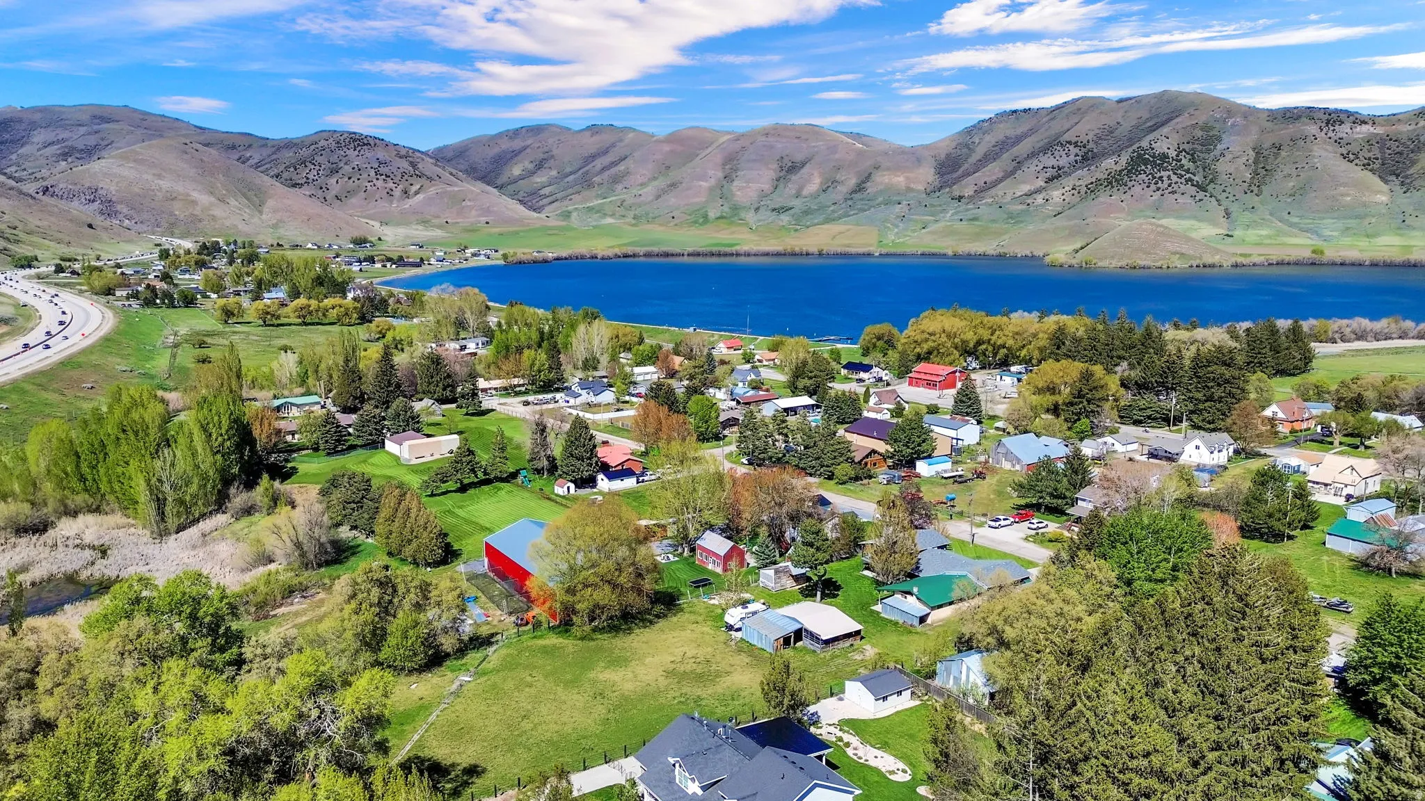 Aerial perspective showcasing a community nestled by a large body of water, with a highway bordering the foreground