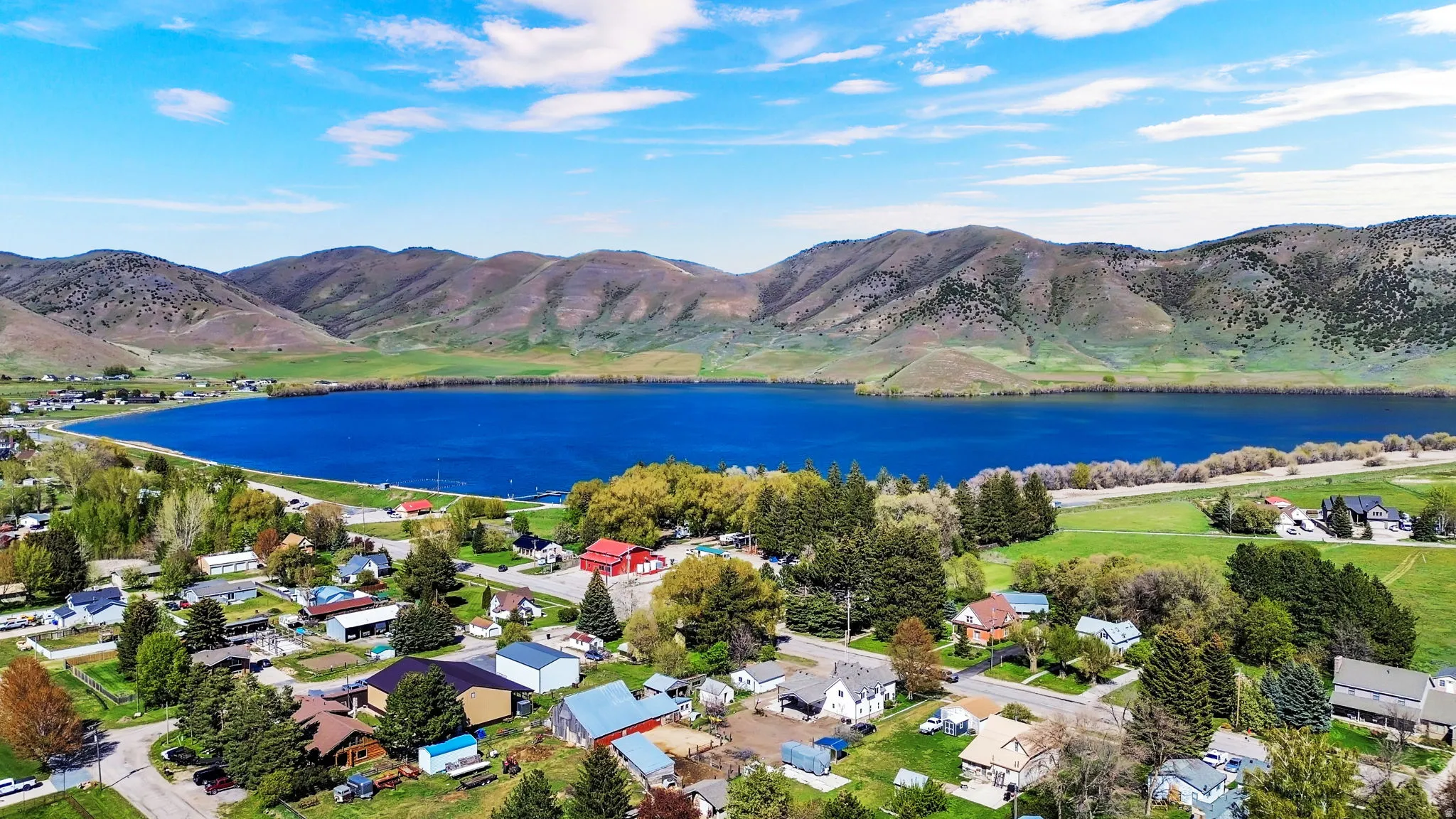 Aerial perspective showcasing a vibrant blue lake bordered by rolling hills and a residential community
