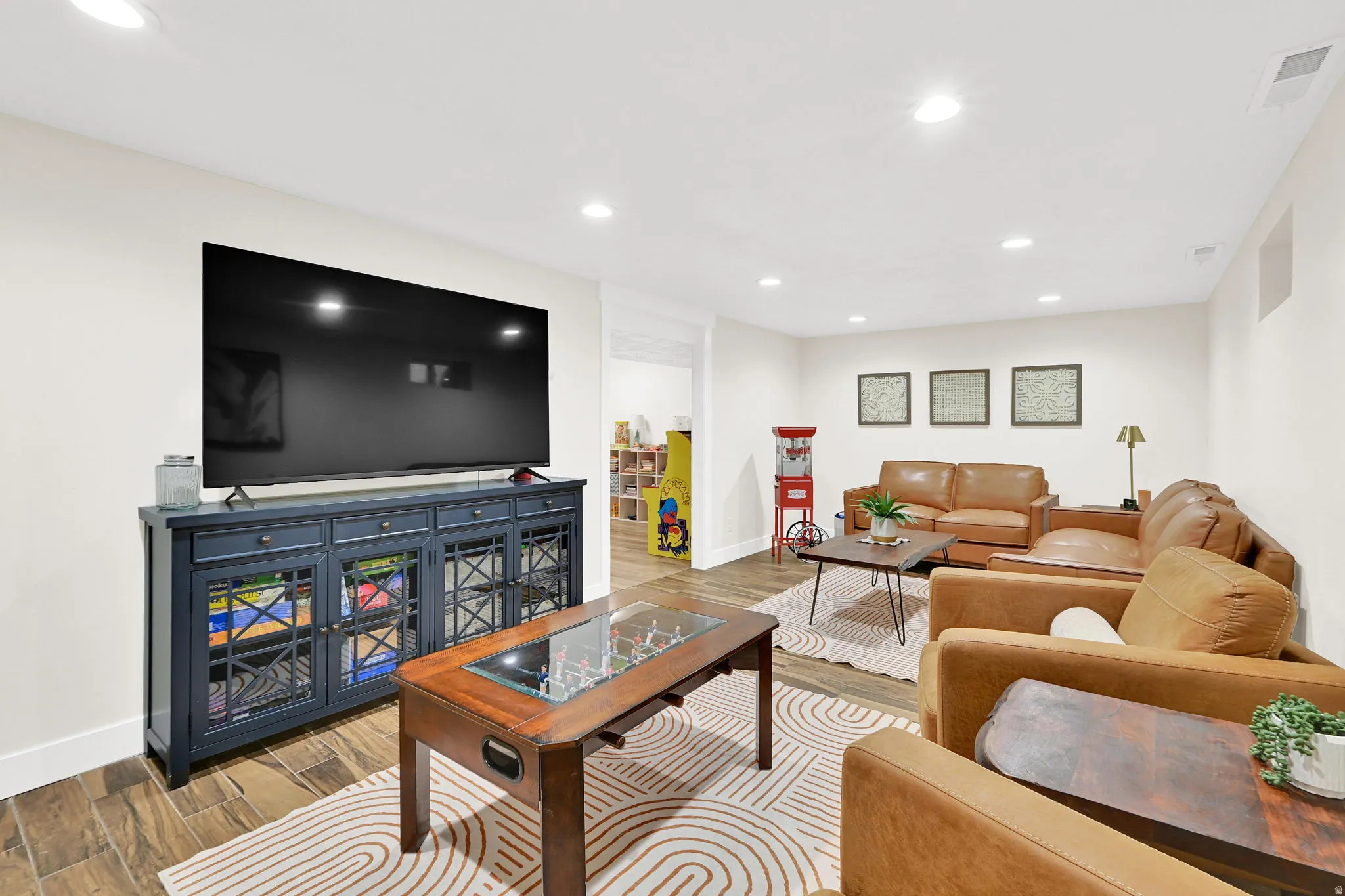 Spacious recreation room featuring recessed lighting, light-colored walls, wood-finish tile flooring