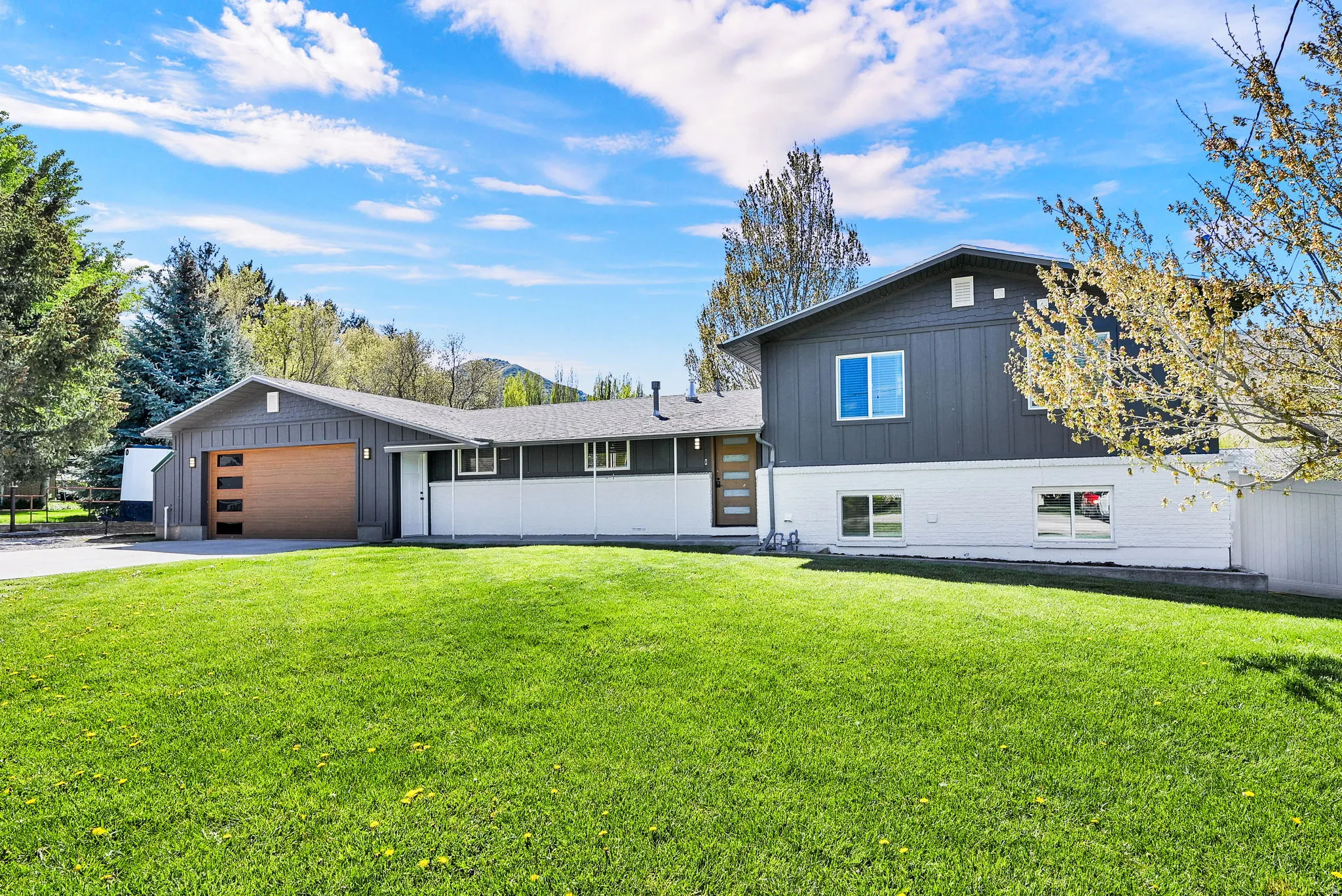 Split-level residence featuring a modern dark gray and white exterior