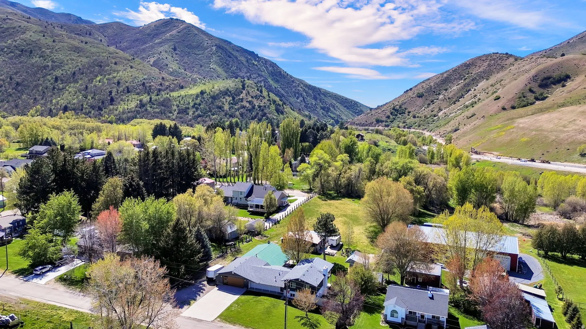 Aerial perspective showcasing the property amidst a lush, verdant valley with substantial mountainous terrain