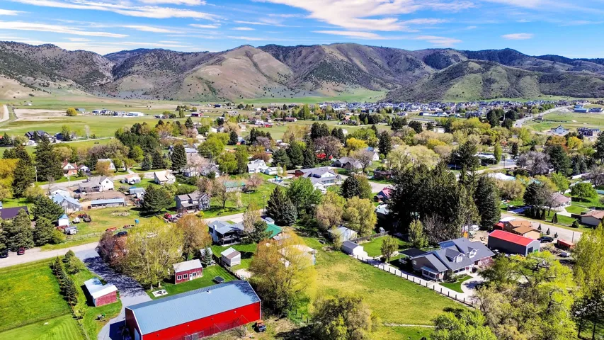 Expansive aerial perspective showcasing a residential community set against a backdrop of rolling mountains and verdant fields
