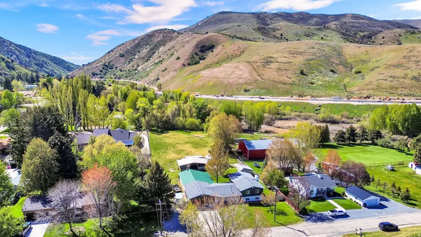 Mountain valley setting featuring residential properties, expansive green spaces, mature trees, and distant highway access