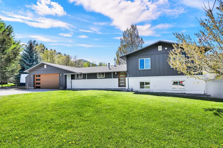 Split-level residence featuring a modern dark gray and white exterior