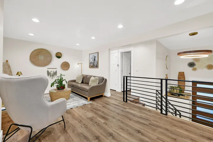 Upper-level living area featuring wood-finish flooring, recessed lighting, and a modern horizontal bar railing