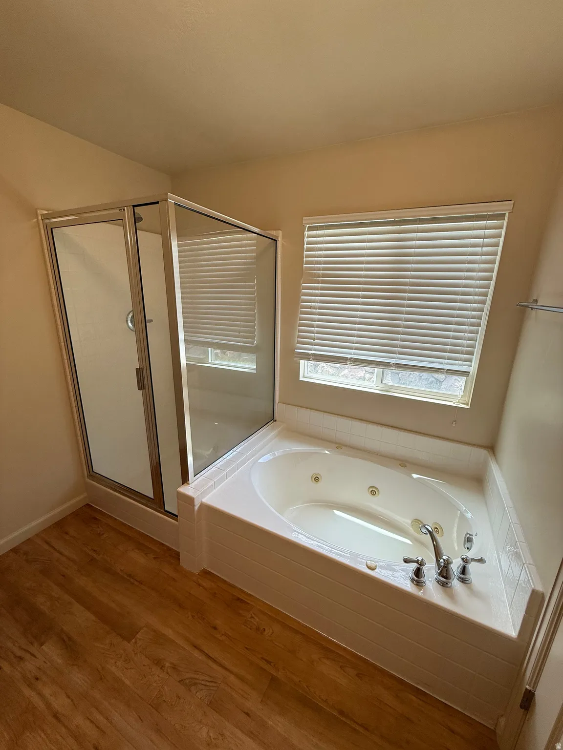 Soaking tub with jetted features and chrome fixtures, accompanied by a separate glass-enclosed shower