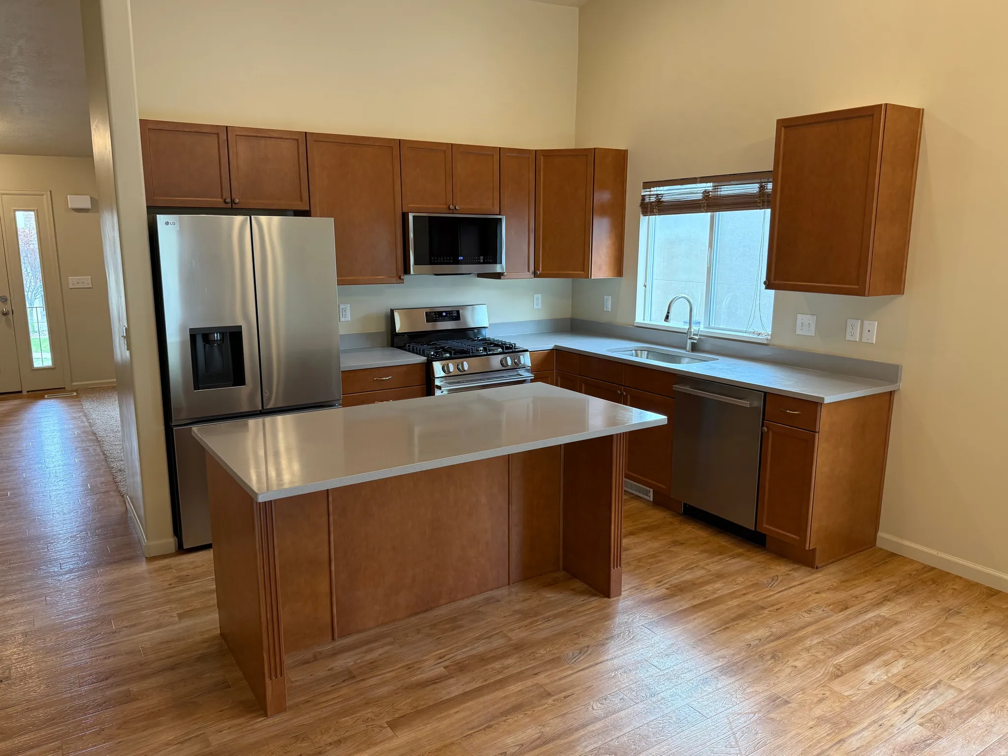Kitchen featuring wood-finish flooring, stainless steel appliances, light-toned countertops, and wood cabinetry