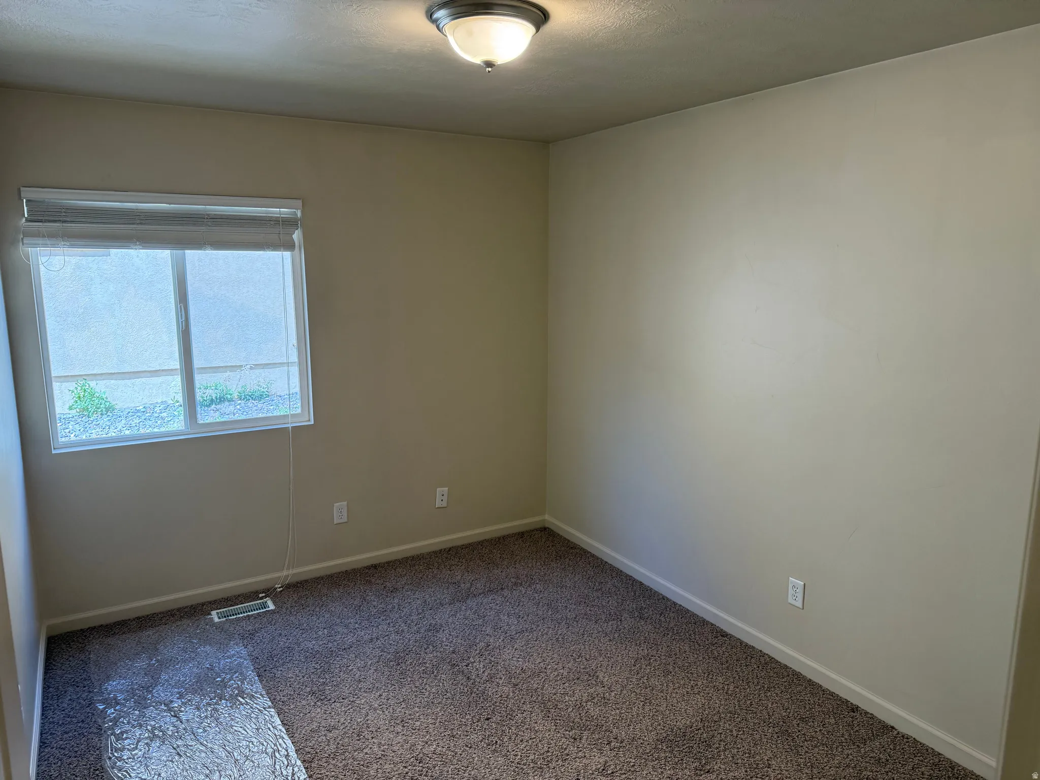 Room featuring a single window with blinds, neutral wall paint, and brown carpeting