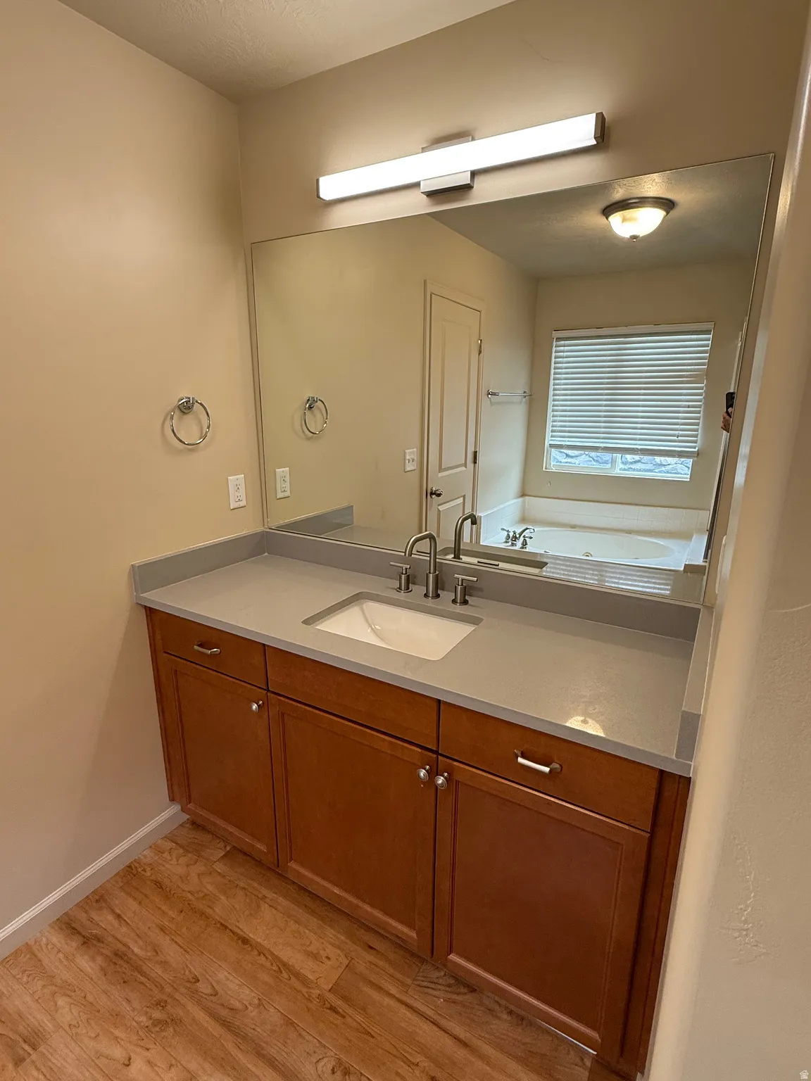 Bathroom vanity featuring a light gray countertop, integrated sink, and wood-finish cabinetry
