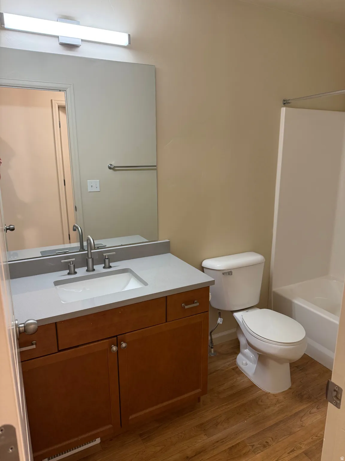 Bathroom featuring a wood-finish vanity with a light-toned countertop and an undermount sink