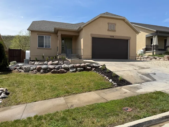 Stucco exterior with an attached garage, a paved driveway, and a front walkway