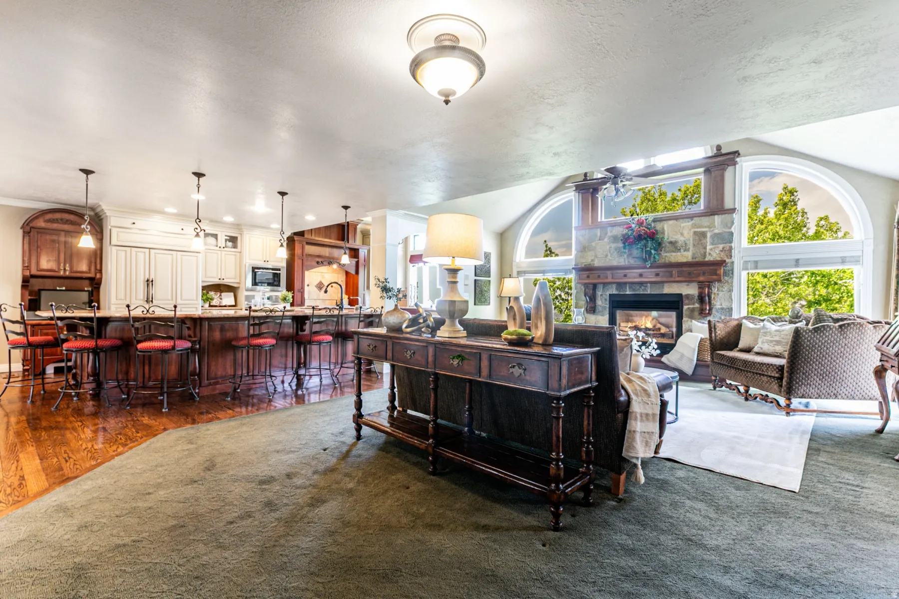 Spacious interior featuring a stone fireplace, arched windows, and a large kitchen island with seating