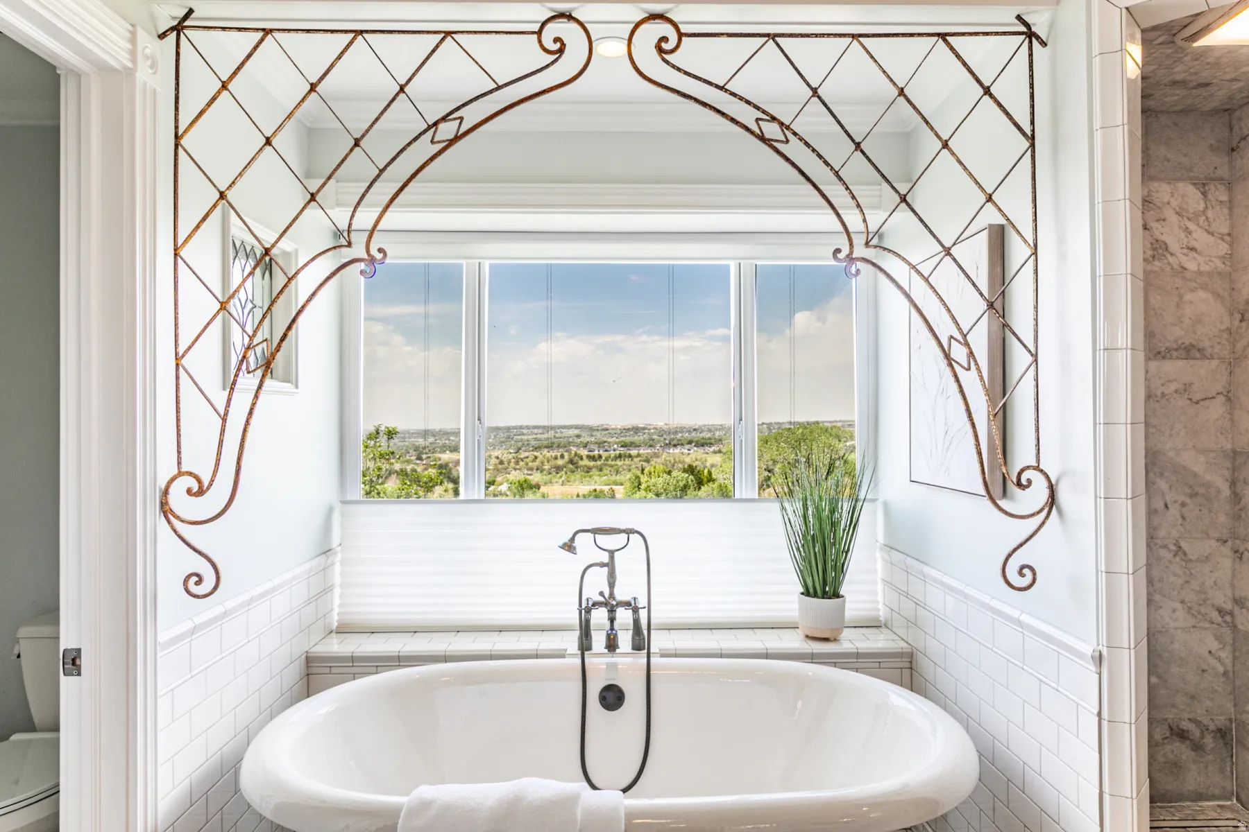 Freestanding soaking tub with a floor-mounted faucet and handheld showerhead