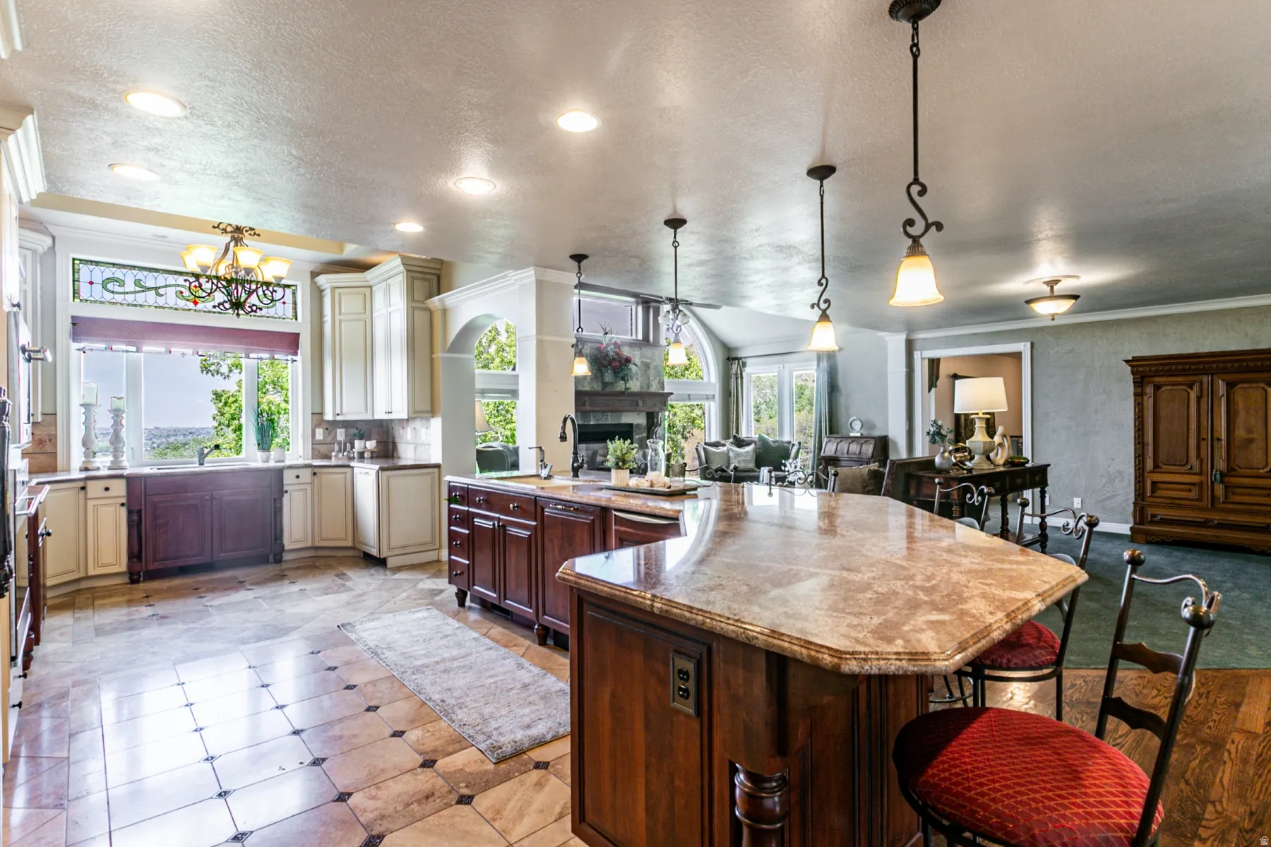 Spacious kitchen featuring a large multi-toned kitchen island with a stone countertop, recessed lighting, tile flooring, and custom cabinetry with an integrated sink