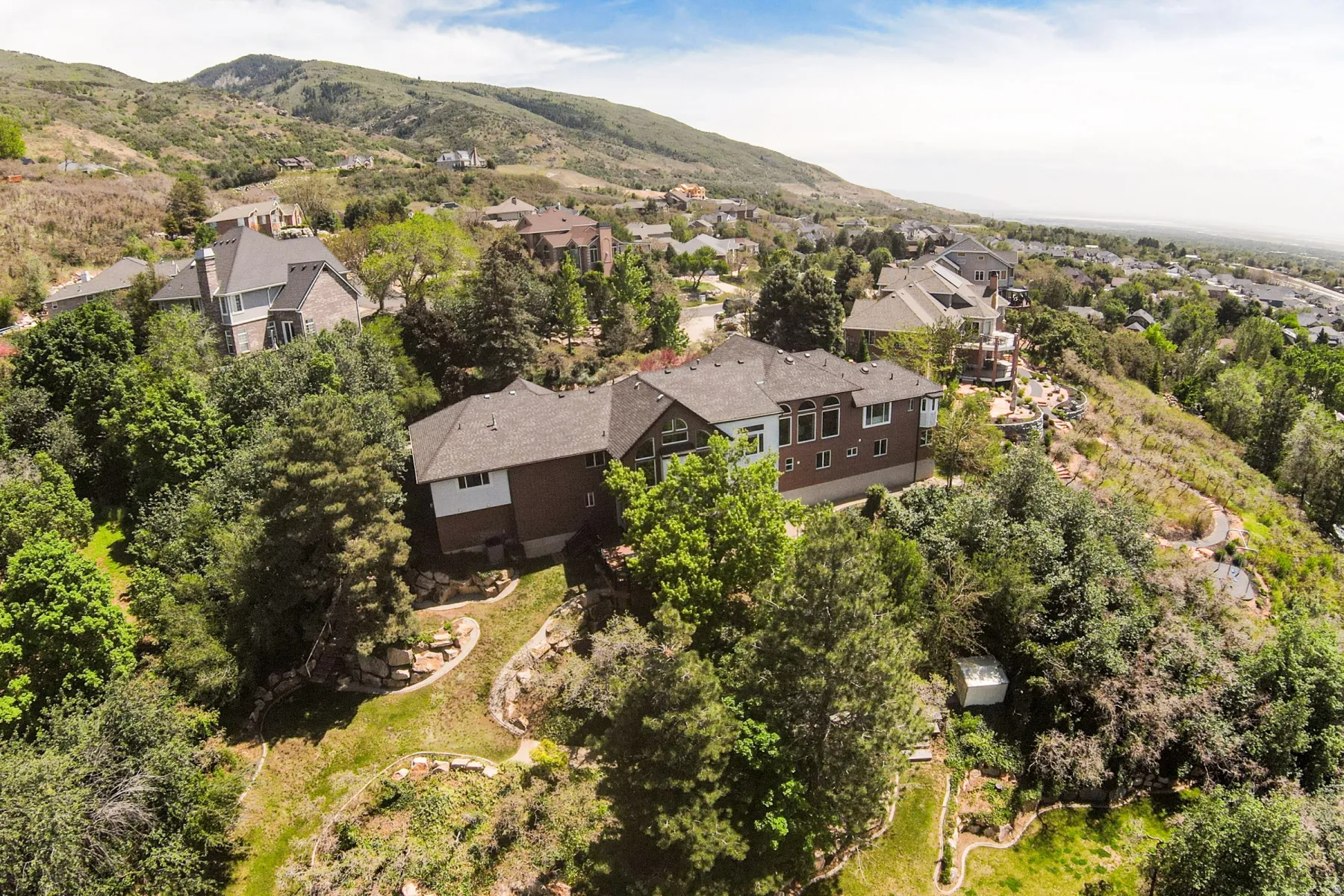 Hillside property featuring a multi-story residence with a brown brick facade and white trim