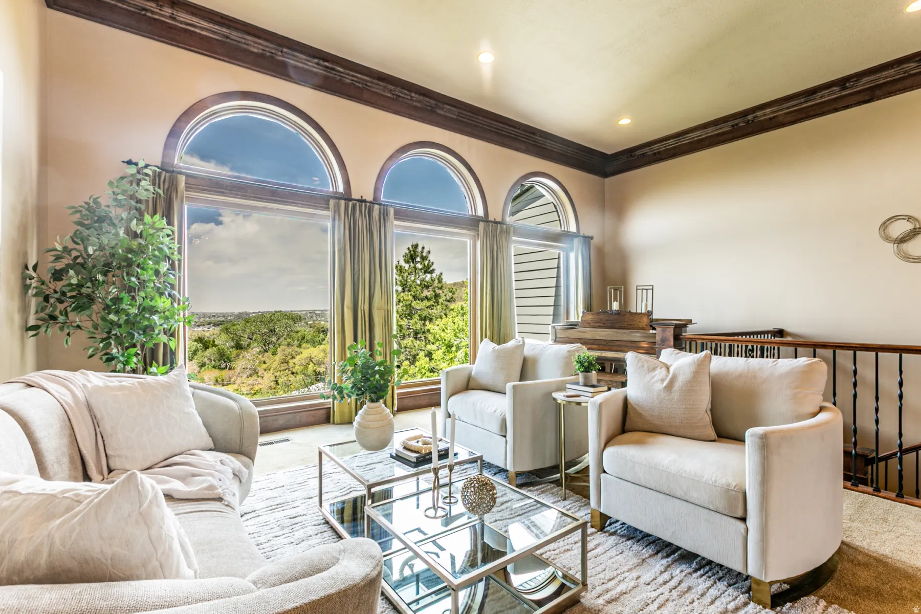 Living area featuring a series of three arched windows, dark wood crown molding, recessed lighting, and a dark staircase railing