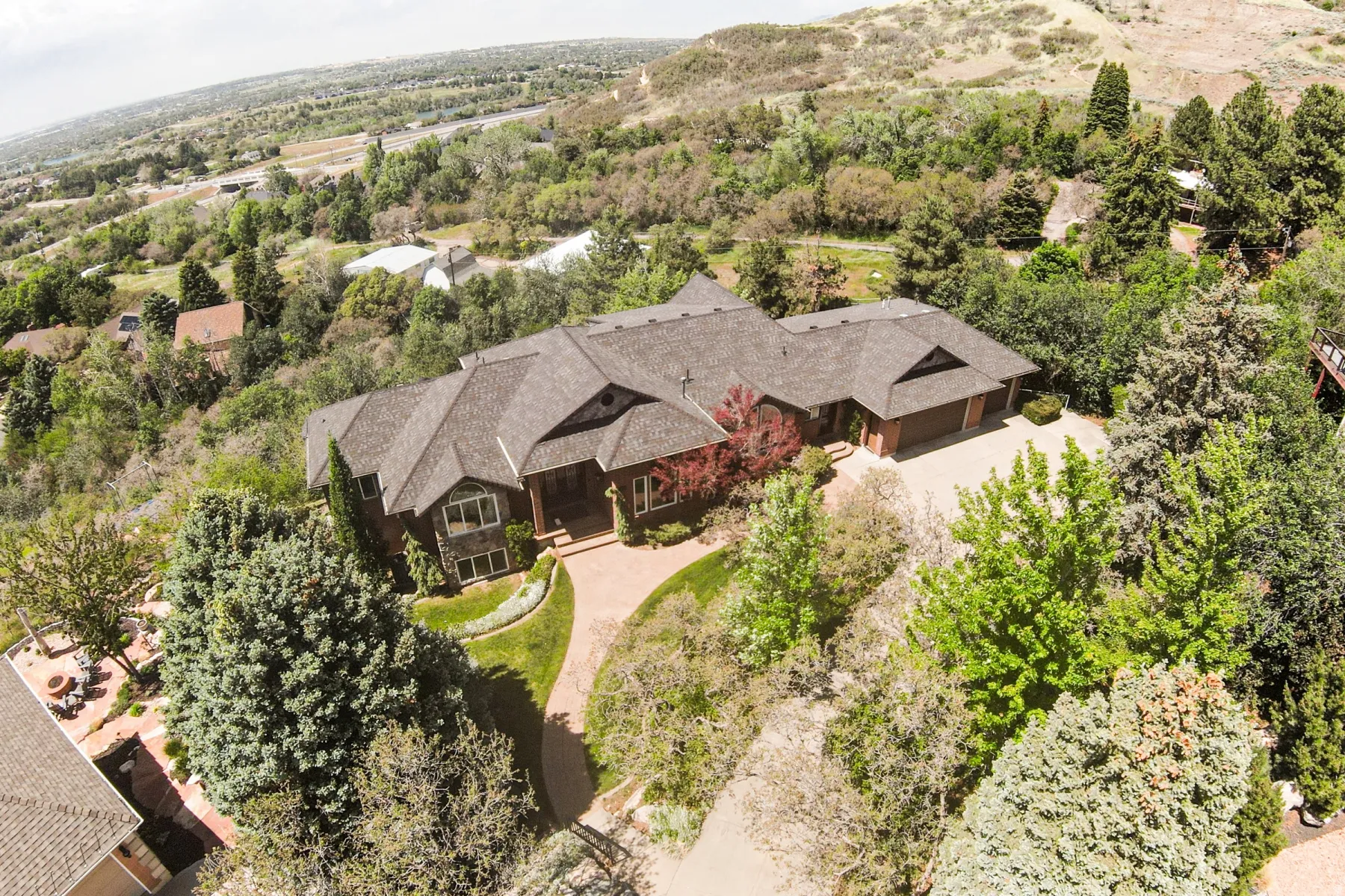 Expansive property featuring a multi-gabled roofline, mature landscaping, an attached garage, and a paved driveway