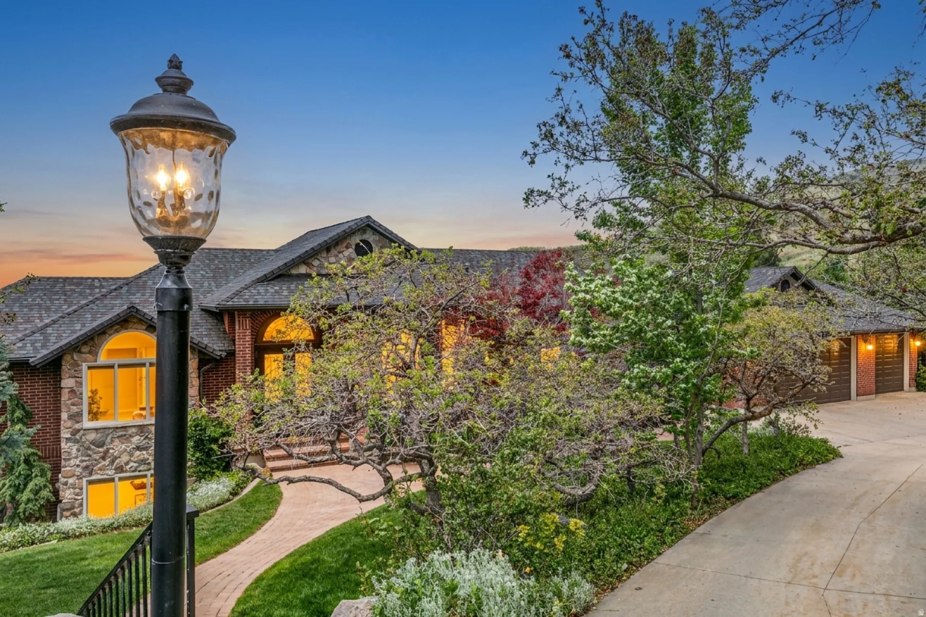 Stone and brick facade residence featuring an arched entry, multiple gables, and an attached two-car garage