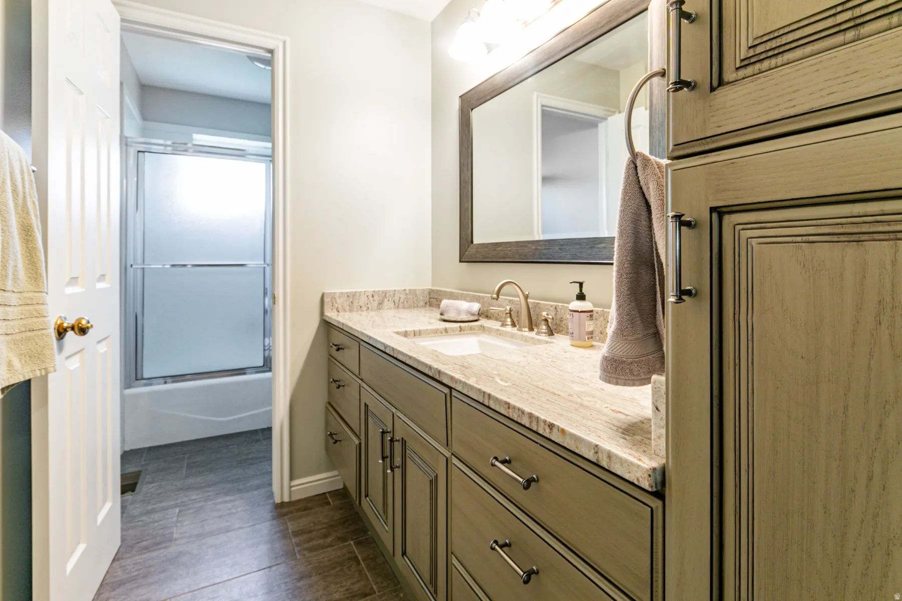 Bathroom featuring a vanity with an integrated sink, a light-colored countertop, and a framed mirror