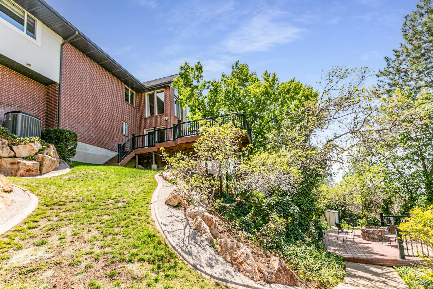 Rear exterior featuring a brick facade and a multi-level wooden deck