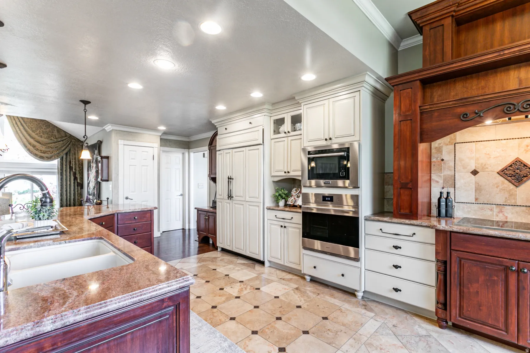 Gourmet kitchen featuring a built-in refrigerator, double ovens, and a large central island with an integrated sink