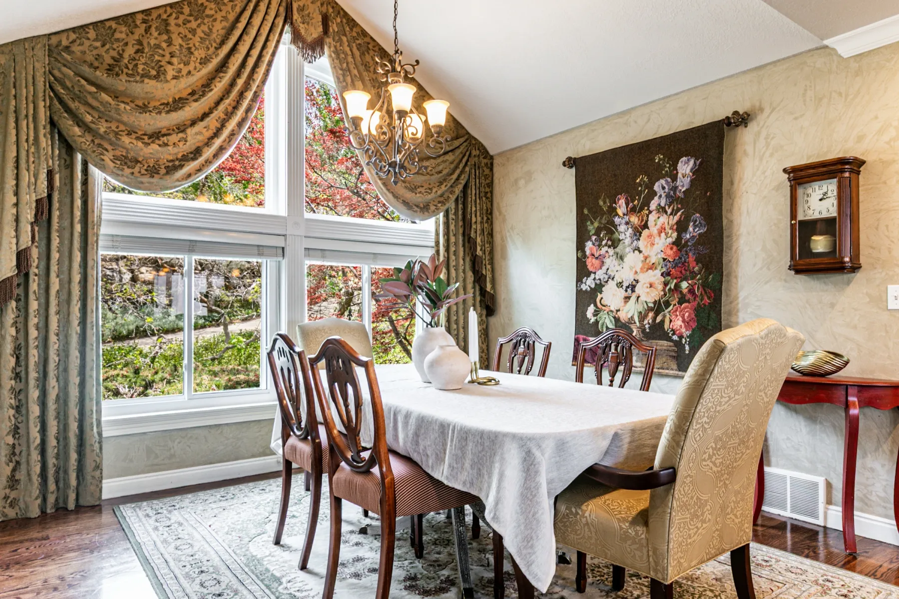 Dining area featuring a vaulted ceiling, a multi-pane picture window, wood-finish flooring, and a decorative chandelier