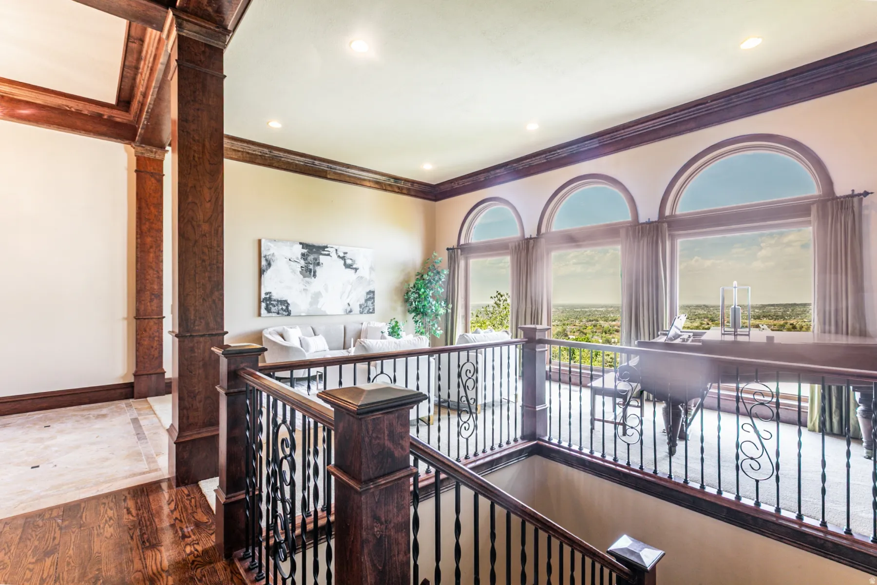Upper-level landing featuring a grand staircase with dark wood newel posts and wrought iron balusters