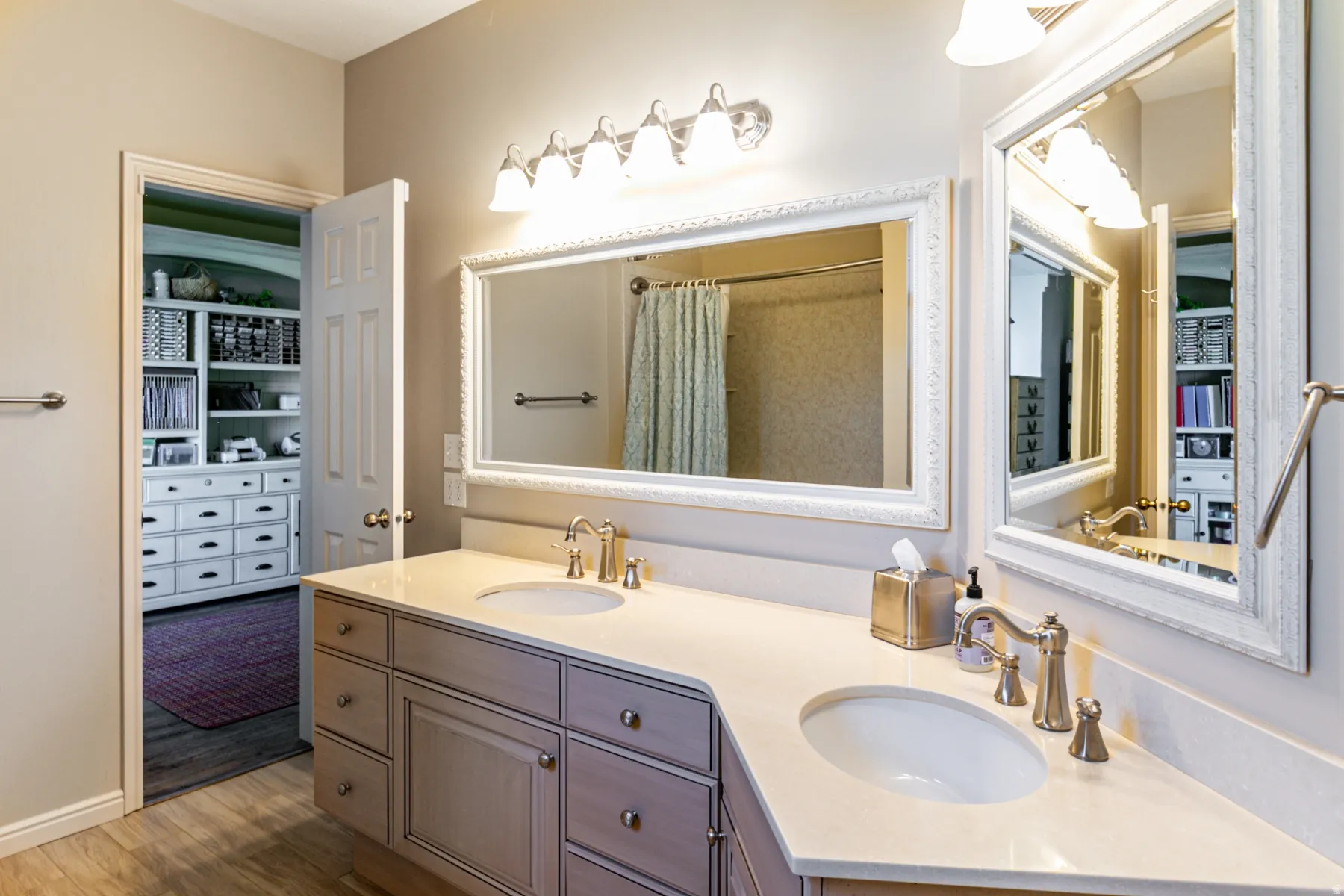 Bathroom vanity with dual sinks, light-toned countertops, and brushed nickel hardware