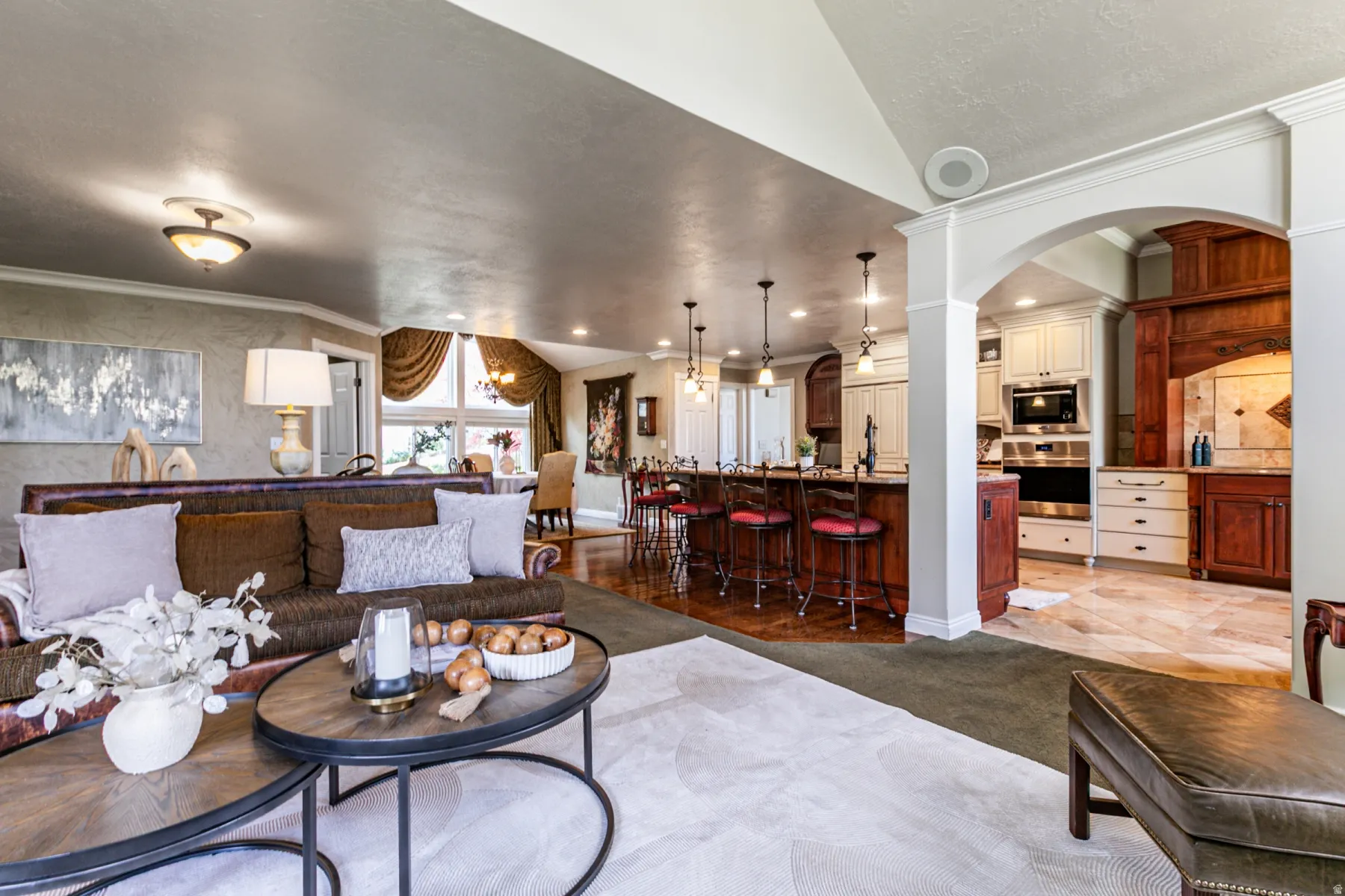 Open-concept living area featuring an arched entryway, recessed lighting, and a blend of carpet and wood-finish flooring