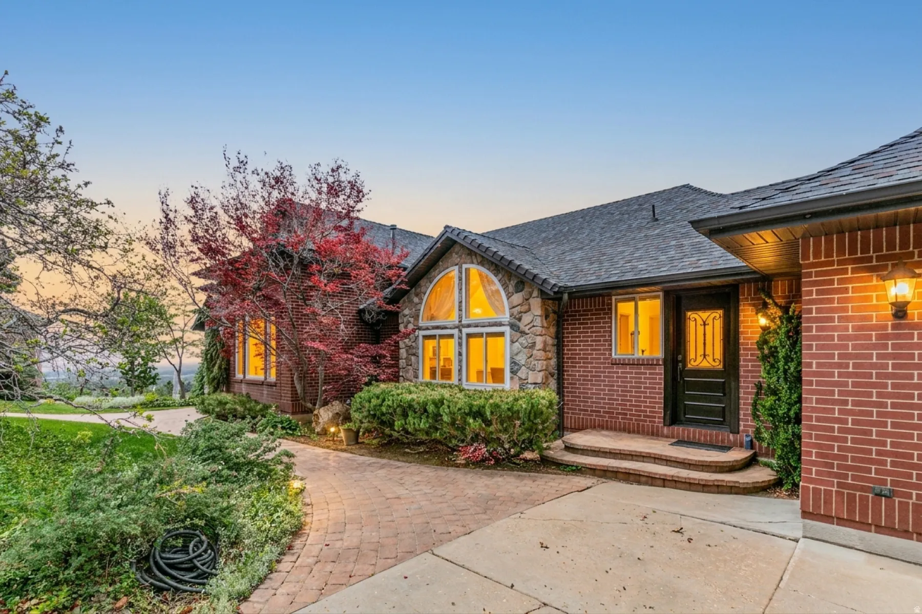 Brick and stone exterior featuring a dark asphalt shingle roof