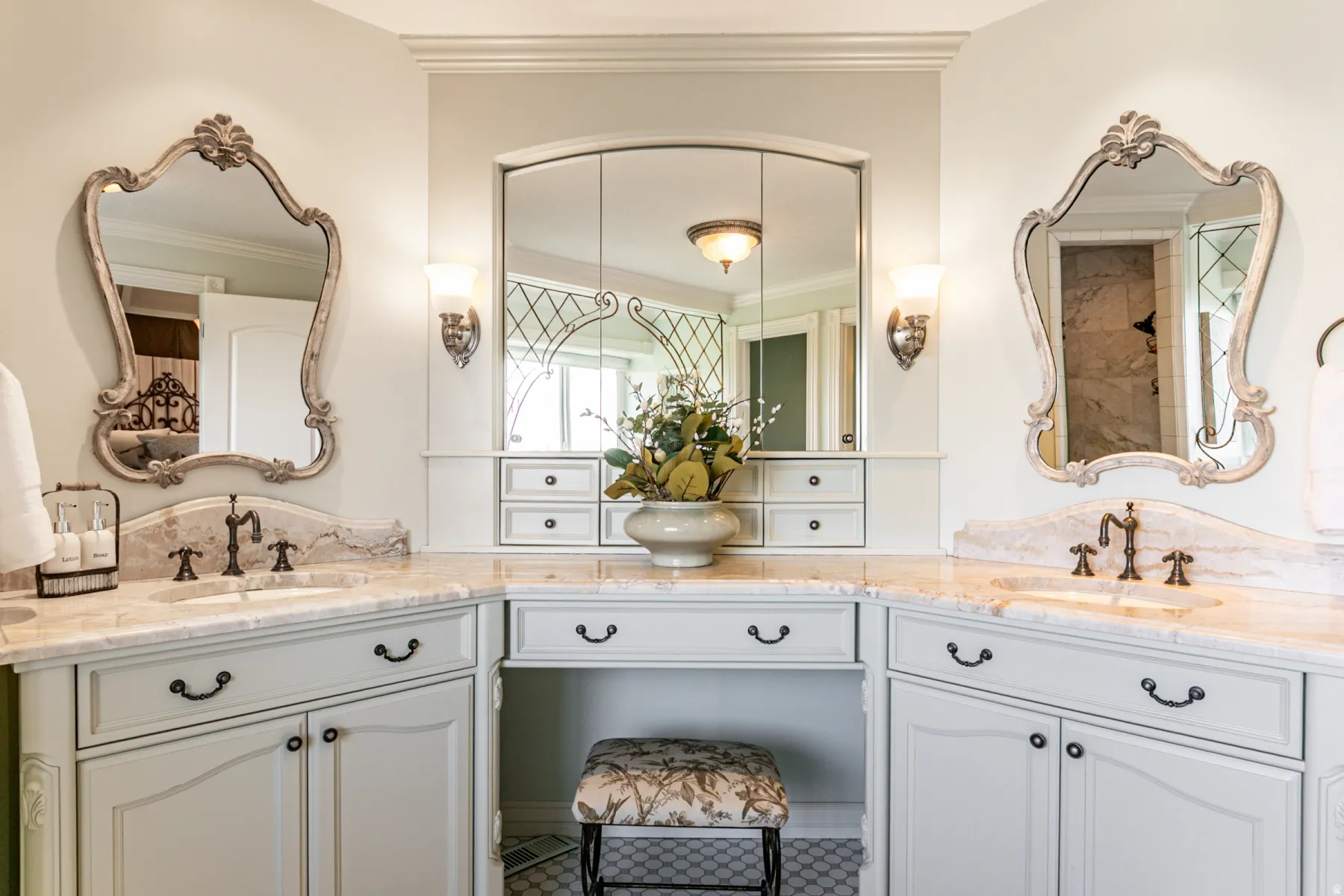 Dual vanity with decorative mirrors, stone countertops, and bronze-finish fixtures