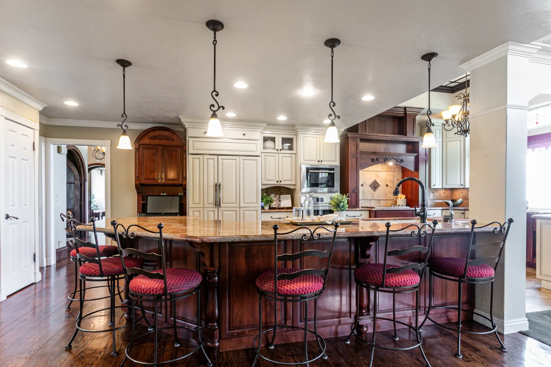 Kitchen featuring a large island with a stone countertop, dark wood-finish cabinetry, and three pendant lights