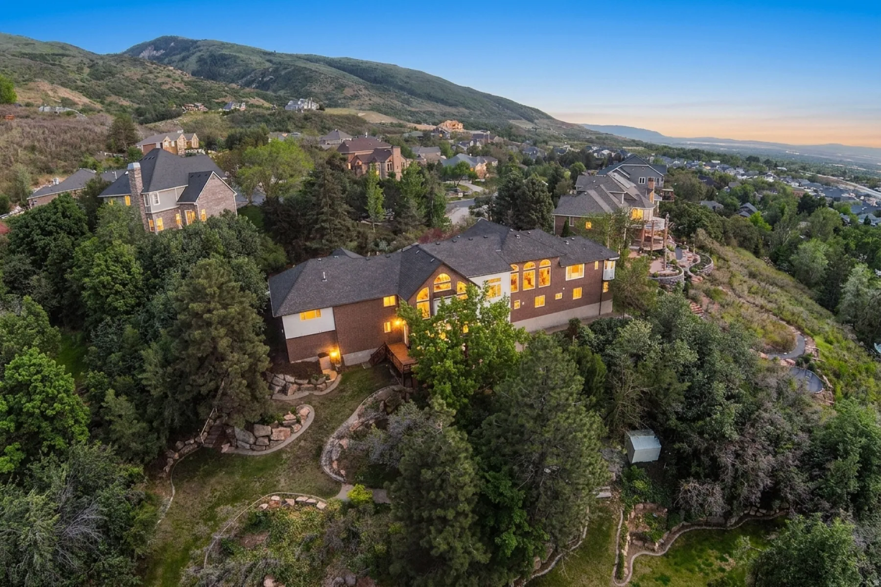 Spacious residence set into a hillside, featuring extensive brick siding, multiple large windows, and a multi-level deck