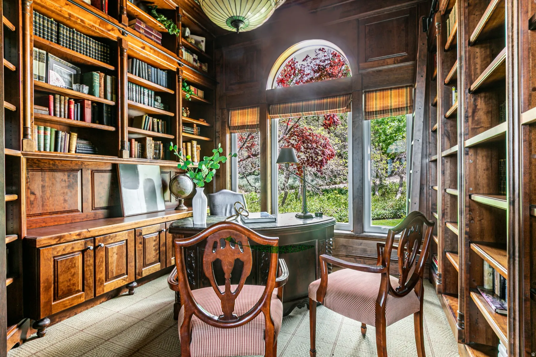 Wood-paneled room featuring extensive built-in shelving, integrated cabinetry, and a large bay window with an arched transom