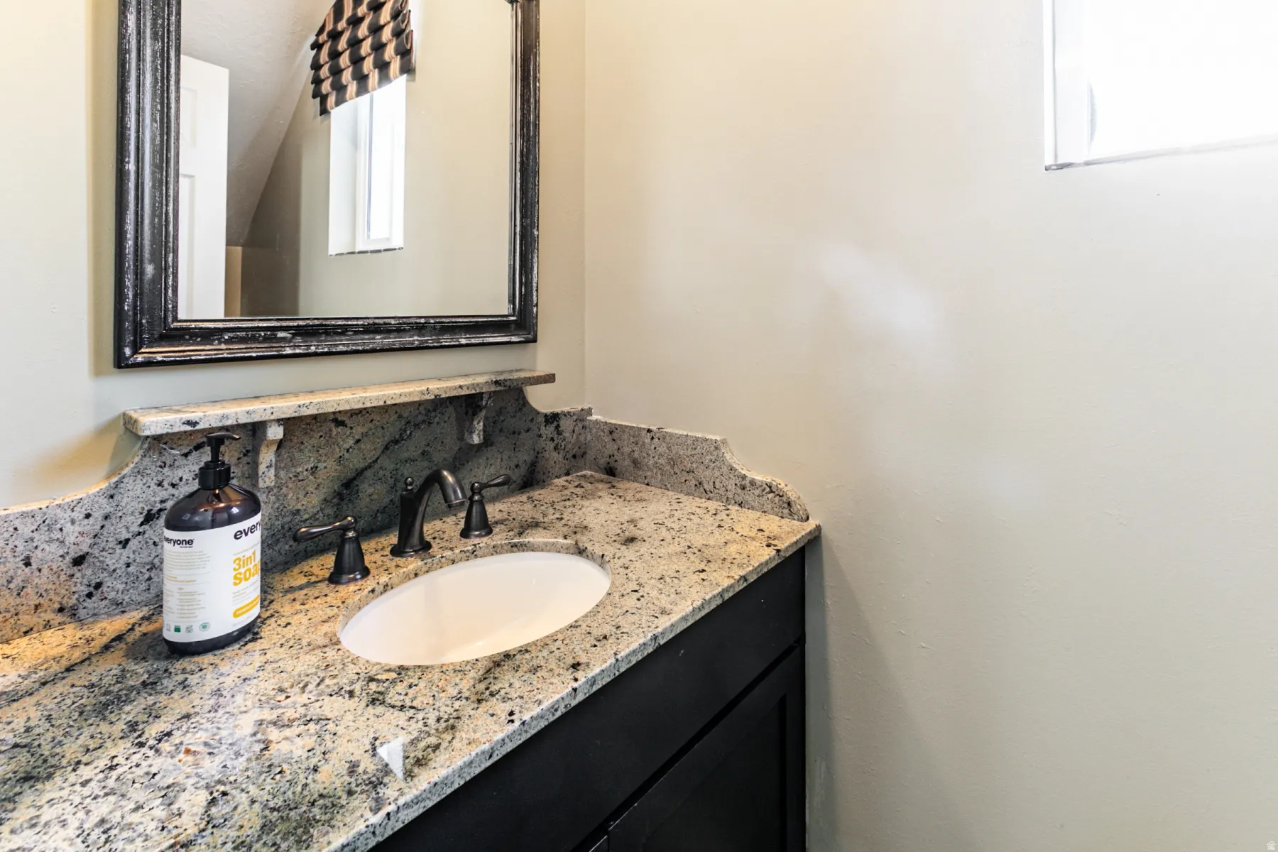 Granite countertop with integrated oval sink and dark bronze faucet