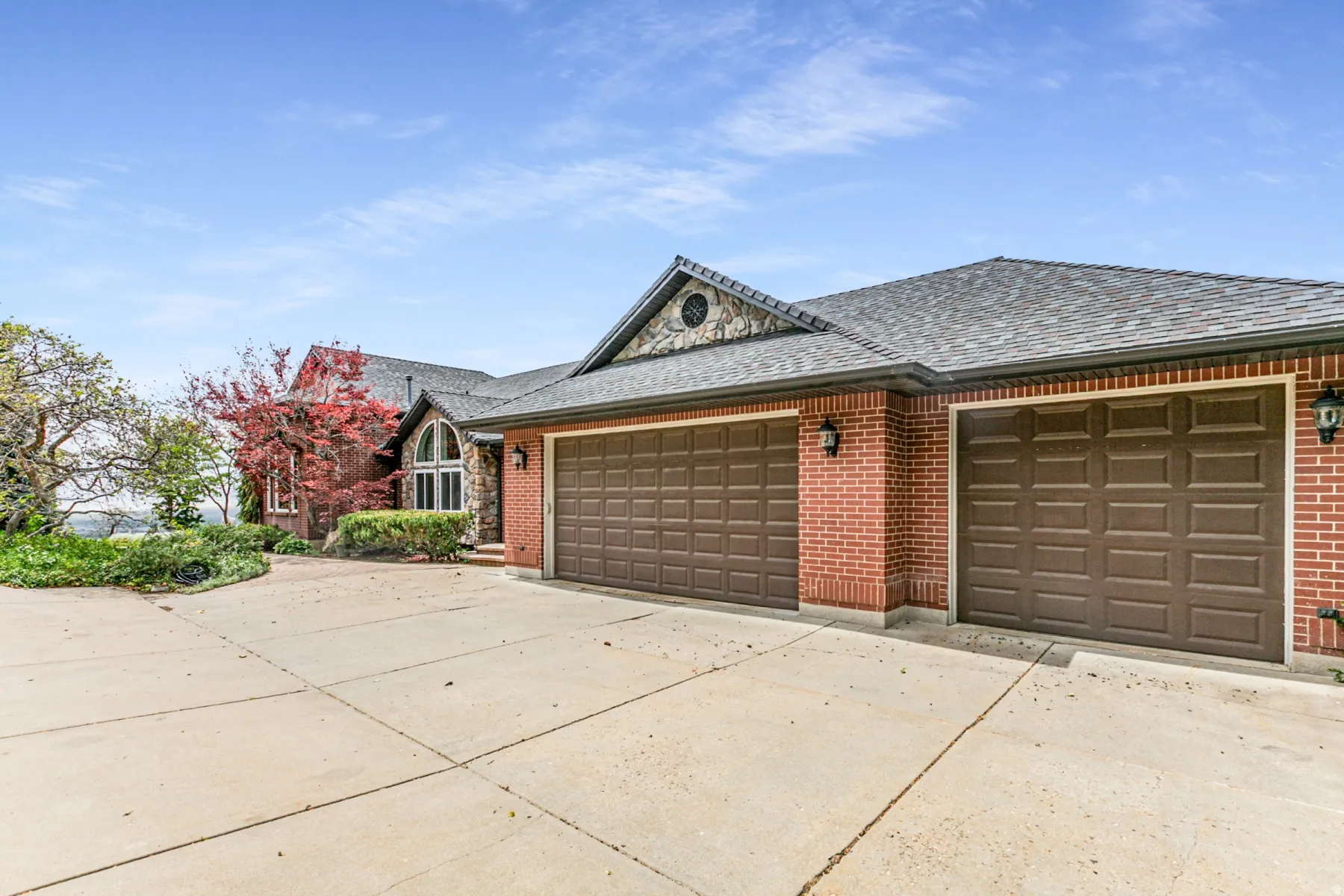 Brick exterior with a stone accent gable, featuring a multi-car garage with panel garage doors