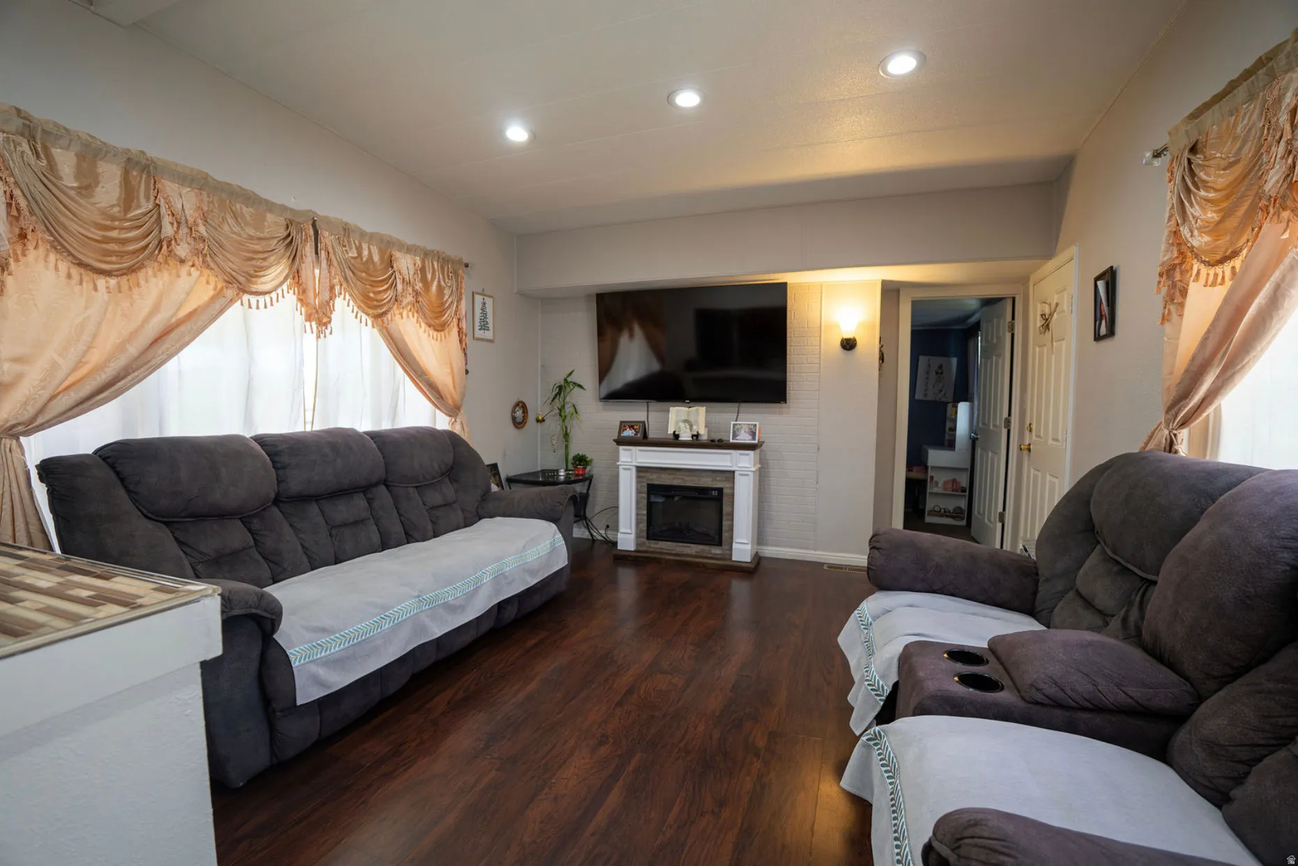 Living area featuring wood-finish flooring, recessed lighting, and an electric fireplace with a white mantel