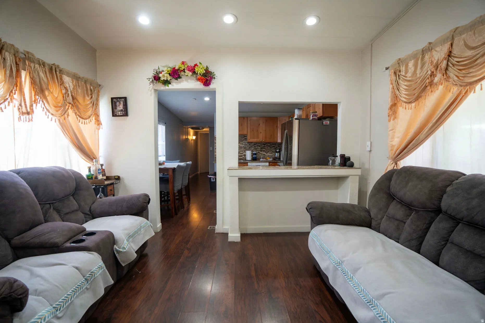 Open concept living area featuring dark wood-finish flooring, recessed lighting, and white wall finishes