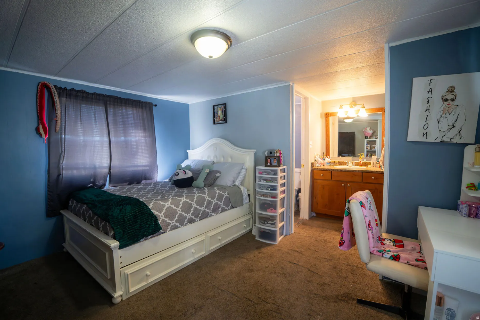 Carpeted bedroom featuring a light fixture, window with blinds, and a built-in vanity with a mirror and lighting