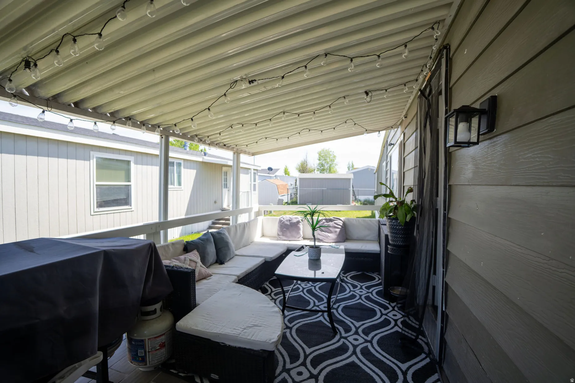 Covered outdoor patio featuring a corrugated metal roof and string lighting