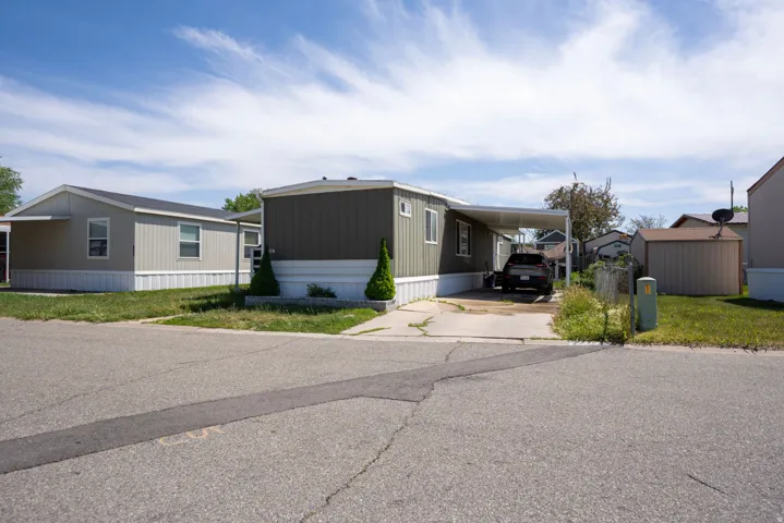 Single-level residence featuring a carport, a paved driveway, and a detached storage shed