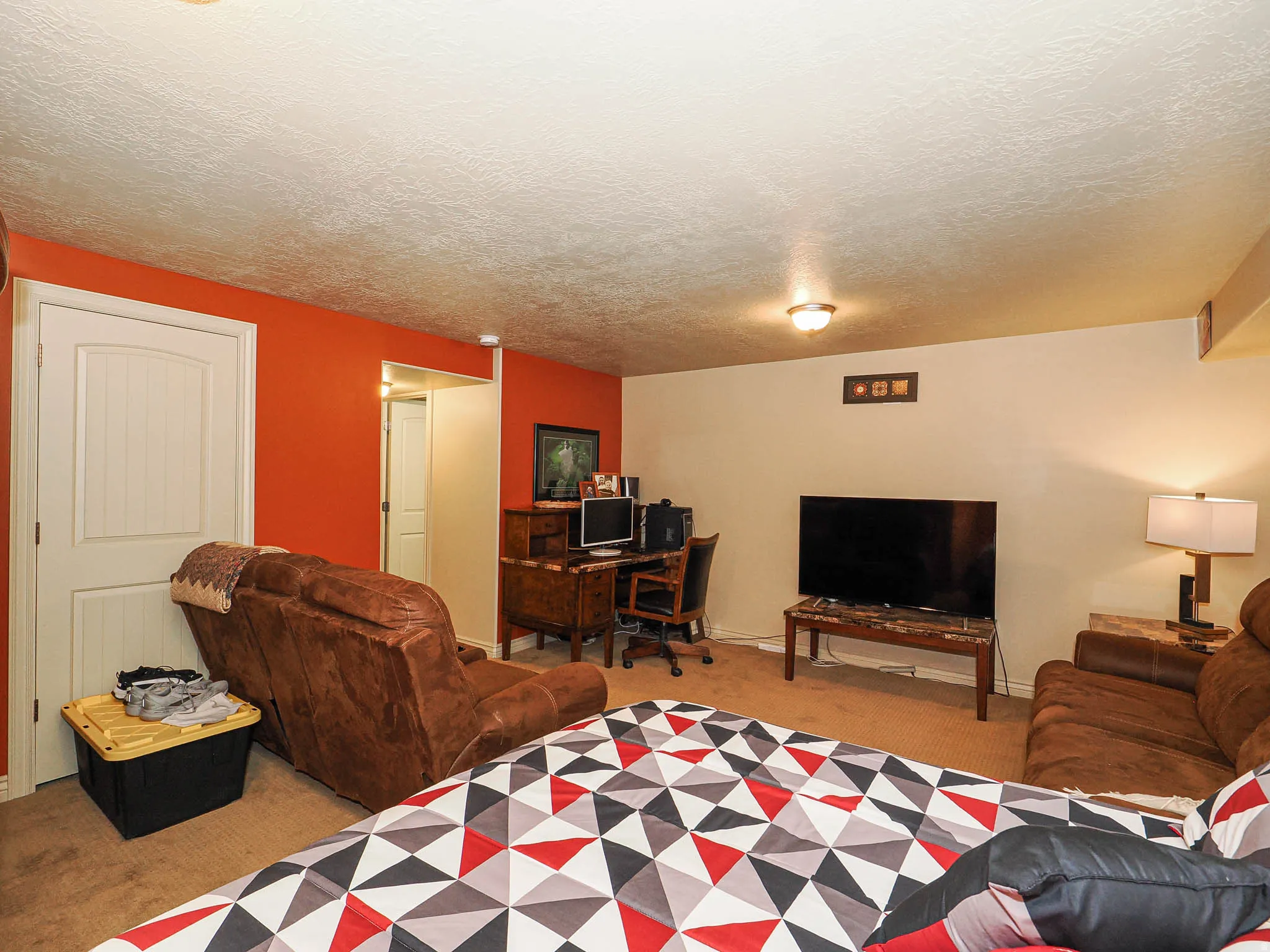 Carpeted interior space featuring a white paneled door, flush-mount lighting, and an accent wall