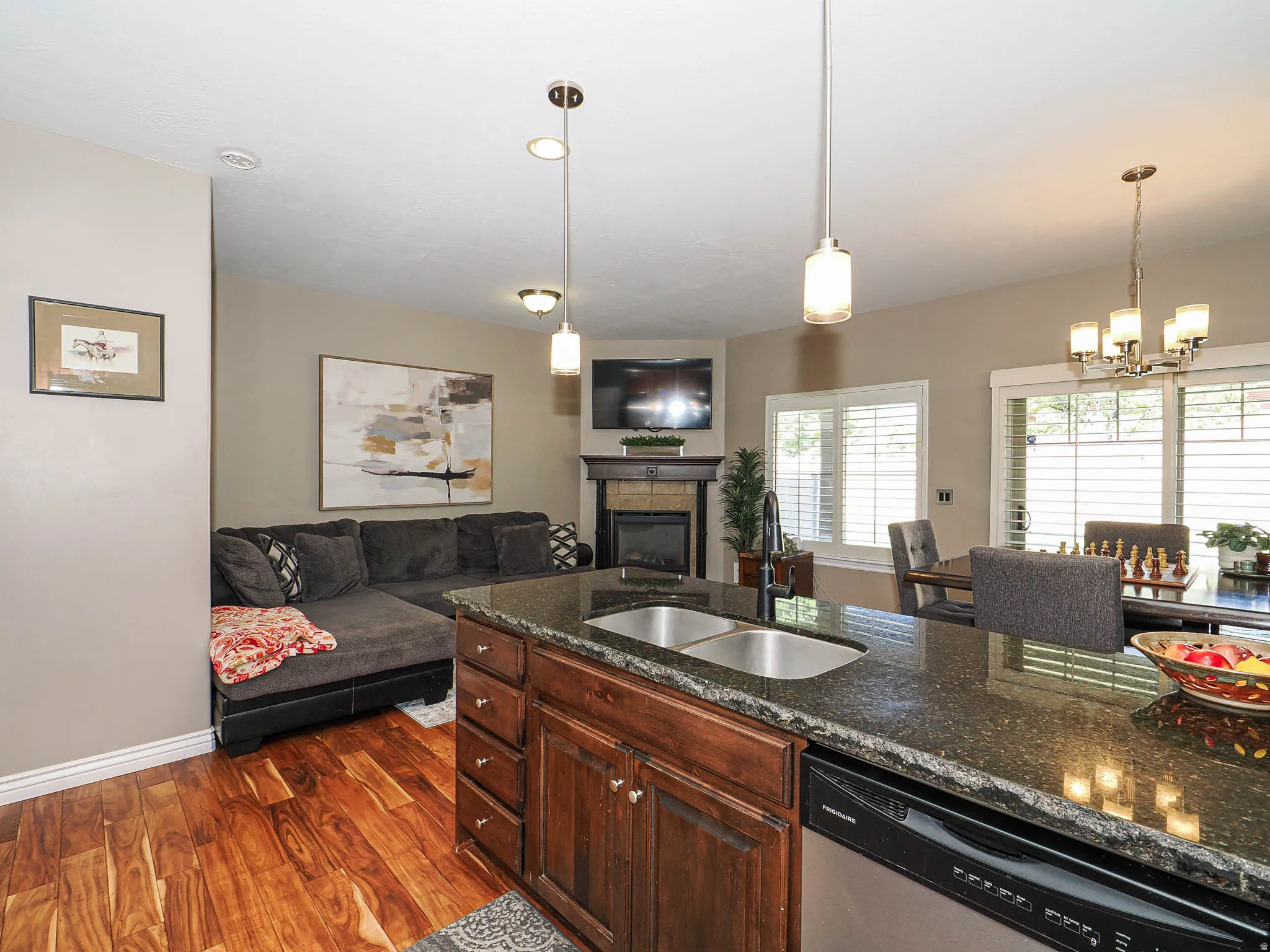 Kitchen island featuring a dual-basin stainless steel sink, dark wood cabinetry, and a black dishwasher