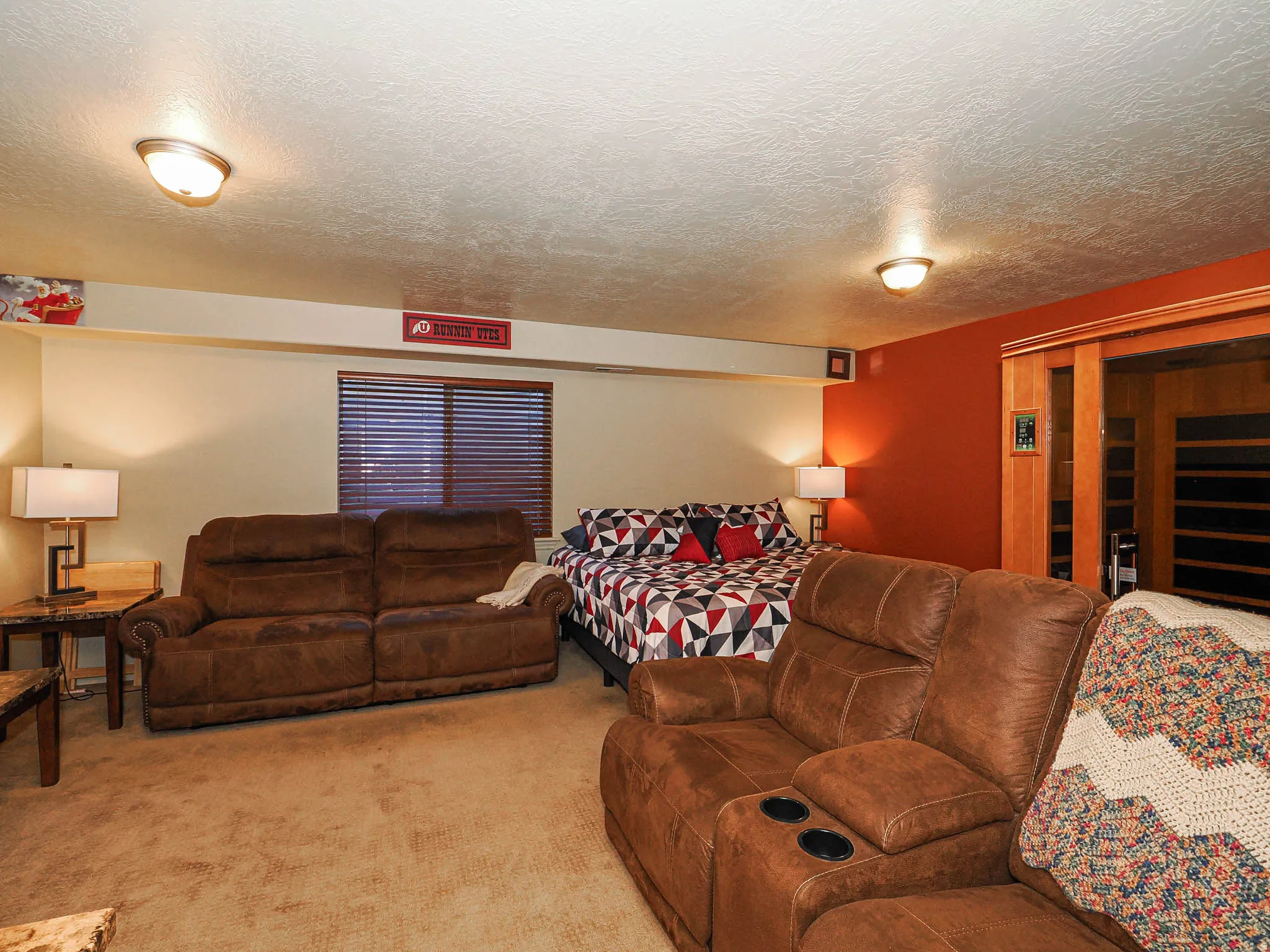 Carpeted room featuring a built-in sauna with wood-paneled trim and a window with blinds