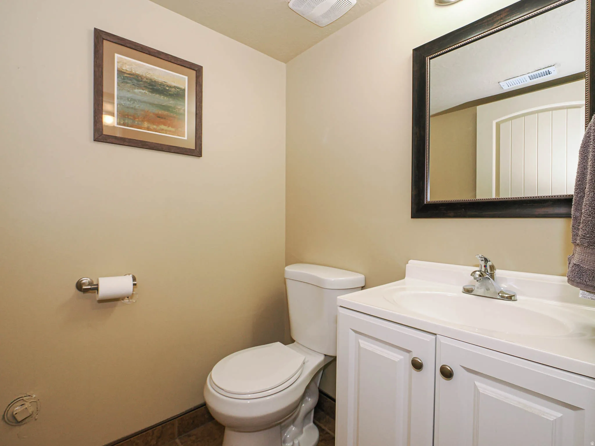Bathroom featuring a white vanity with built-in sink, brushed nickel faucet, and a large framed mirror