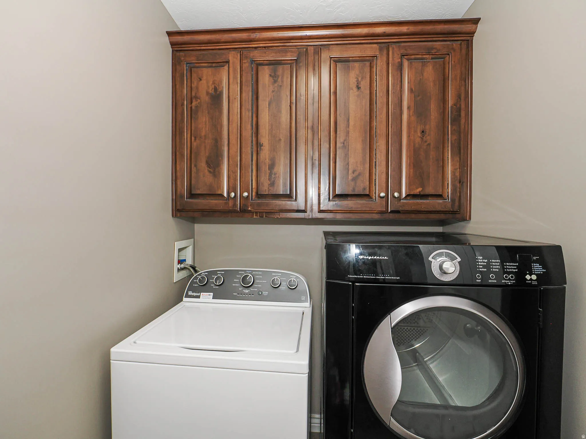 Wood-finish upper cabinetry with crown molding and silver hardware