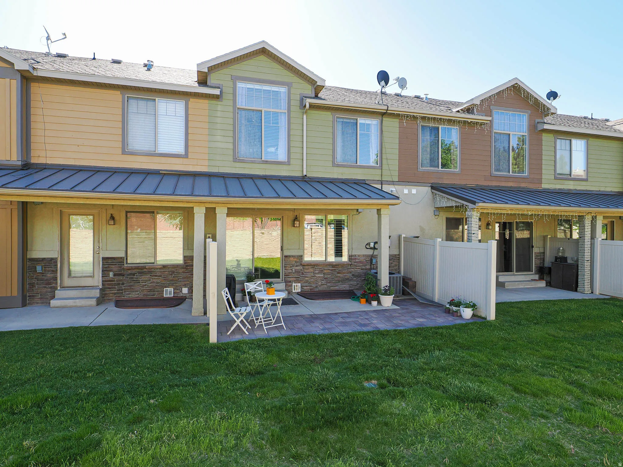 Rear exterior featuring covered patios with exposed beams, brick veneer accents, and a fenced yard with a paver patio area