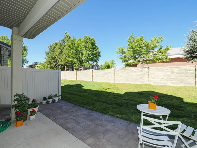 Expansive backyard featuring a lush lawn, paver patio, concrete patio, a tall privacy fence, and a decorative block wall