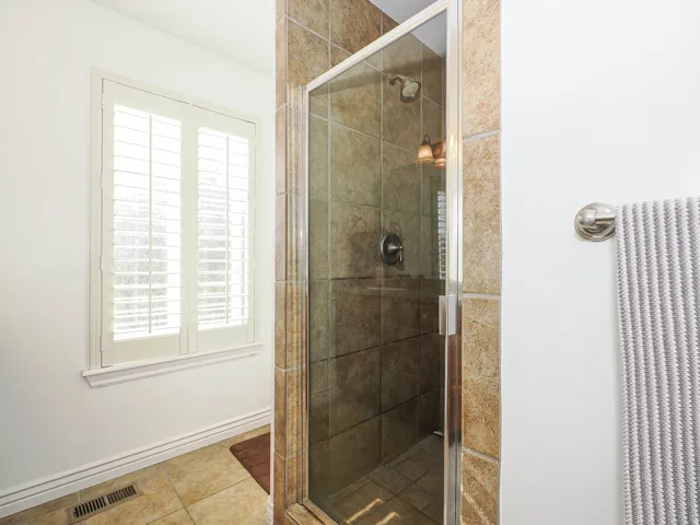 Glass-enclosed shower with tile surround and brushed nickel fixtures